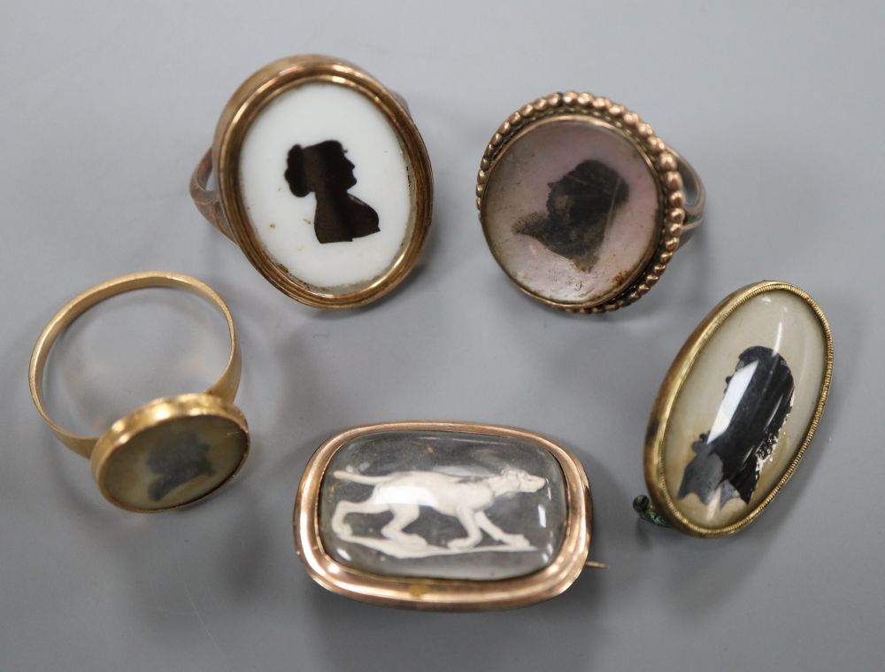 Three assorted yellow metal and glazed silhouette rings and two brooches, including sulphide dog, gross 21.2 grams.